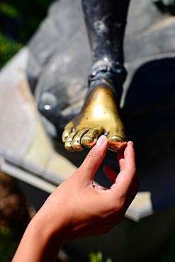 Tourist touching statue•s feet at The Achilleion Palace in Village of Gastouri (Sisi's beloved Greek summer palace), Corfu, Greece