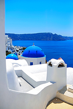 Hillside buildings with traditional church blue domes in Oia, Santorini, Greek Islands, Greece