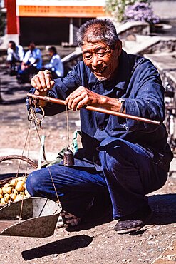 A vendor with a hand balance scale in the farmers market in Mutianyu, China