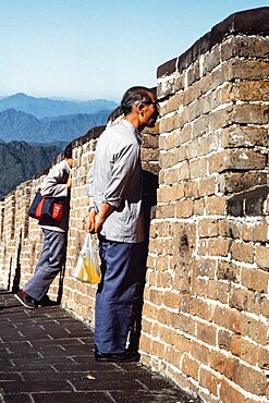 Chinese tourists looking at the landscape from the Great Wall at Mutianyu, China.