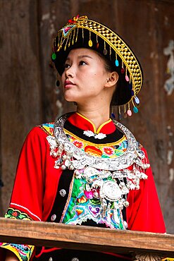 An attractive young woman in traditional ethnic Tujia dress poses for a portrait in Furong, China.