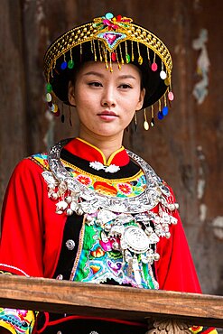 An attractive young woman in traditional ethnic Tujia dress poses for a portrait in Furong, China.