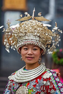 A young woman poses in the traditional ceremonial dress of the Tujia ethnic minority in Fenghuang, China.