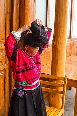 A woman of the Red Yao ethnic minority fixes her traditional long hair. Jinkeng, Longshen, China.