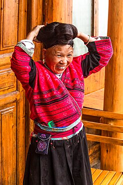 A woman of the Red Yao ethnic minority fixes her traditional long hair. Jinkeng, Longshen, China.