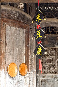 Woven bamboo baskets & a banner with Chinese characters decorate an old building in Furong, China.