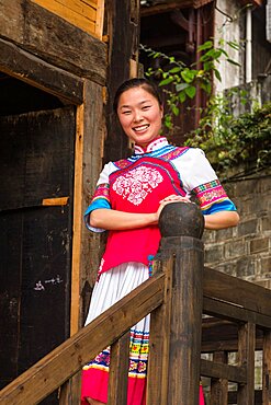 An attractive young woman in traditional ethnic Tujia dress poses for a portrait in Furong, China.