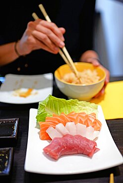 Woman eating white rice with sashimi