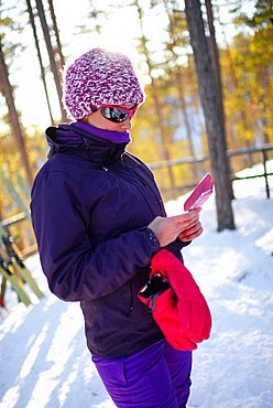 Young attractive woman using mobile telephone in Pyha ski resort, Lapland