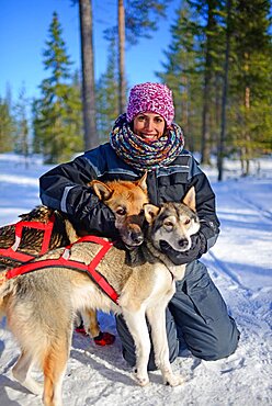 Young woman receives love from friendly dogs. Wilderness husky sledding taiga tour with Bearhillhusky in Rovaniemi, Lapland, Finland