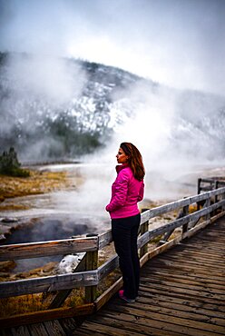 Young woman looking at geyser in Yellowstone National Park, USA