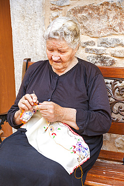 Elderly woman sewing embroidery, in the village of Pyrgi, Chios, Greece