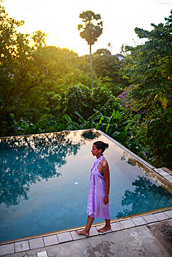 Young attractive woman enters an infinity edge swimming pool at The Dutch House, Galle, Sri Lanka