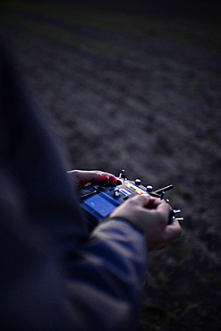 Young man flying a quadcopter DJI phantom drone outdoors