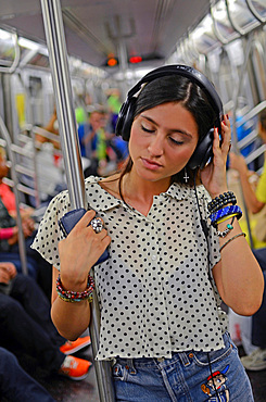 Attractive young mixed race woman traveling in subway train, New York City