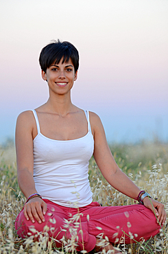 Attractive short haired woman practices yoga in nature