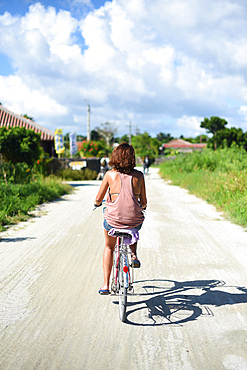 Young woman rides bike in Taketomi Island, Okinawa Prefecture, Japan