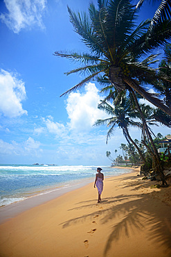 Young woman walking on Hikkaduwa beach at sunset, Sri Lanka