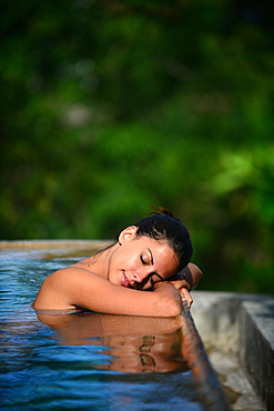 Young attractive woman enjoying a bath in the infinity edge swimming pool at The Dutch House, Galle, Sri Lanka