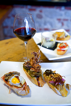 Small portions of food or tapas and a wine glass in a restaurant.