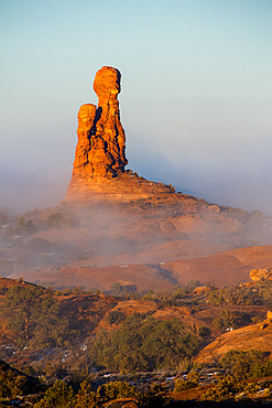 An unnamed Entrada sandstone rock spire in a sea of fog in a winter temperature inversion in Arches National Park, Moab, Utah.