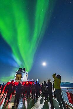 Passengers observing and shooting the Northern Lights from the upper Deck 9 of the ms Trollfjord on the northbound voyage, Oct 16, 2019, north of Tromsø. Illumination is from the waning gibbous Moon in frame at right.