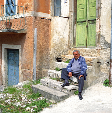 Old man sitting on steps in the old part of the town of Capolaterra, Norcia, Umbria, Italy, Europe