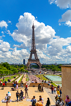 Breathtaking view of the Eiffel Tower on a sunny day with fluffy clouds, surrounded by tourists and greenery, Paris, France, Europe