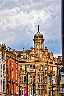 A historic building with ornate architecture, featuring a prominent turret and decorative details. The sky is cloudy, adding a dramatic backdrop to the scene.