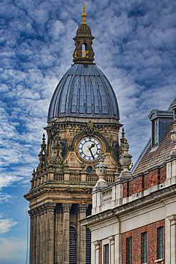 A close-up view of a historic clock tower with a domed roof, featuring intricate architectural details and a large clock face. The sky is partly cloudy, adding depth to the scene.