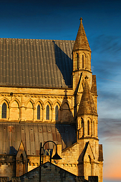 Architectural detail of a church facade. Stone construction with turrets, roof, and windows against a blue and orange sky in York, UK.