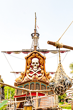 A partially visible pirate ship structure with skull and crossbones decor, ropes, mast, and netting against a bright sky at Disneyland Paris.