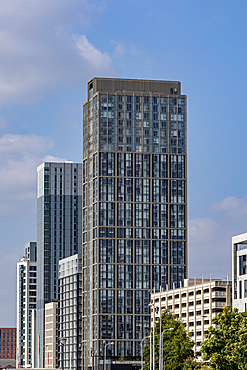 A cluster of modern, high-rise buildings with glass facades against a partly cloudy blue sky in Liverpool, UK.