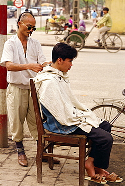 A street hair stylist on the pavement in the centre of the city of Hanoi, Vietnam, Indochina, Southeast Asia, Asia