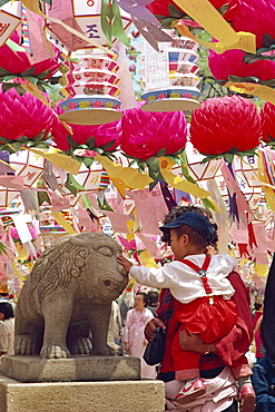 Small child stroking a statue during the Buddha's Birthday at Chogye Sa, near Seoul, South Korea, Asia