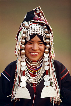 Portrait of a smiling woman of the Akha hill tribe wearing head-dress of silver and coins, in the Golden Triangle, Thailand, Southeast Asia, Asia