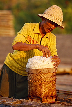 Portrait of a man piling salt into a basket on the east coast of the island of Bali, Indonesia, Southeast Asia, Asia