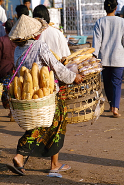 Woman carrying two baskets of French bread in the Talaat Sao Market in Vientiane, Laos, Indochina, Southeast Asia, Asia