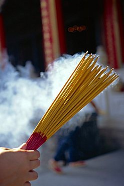 Hand holding smoking incense sticks in Hong Kong, Asia