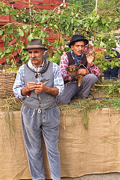 Two men in traditional costume, one holding a dog, at the annual Autumn Wine and Food Parade, Asti, Piedmont, Italy, Europe