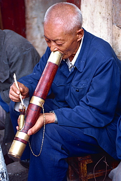 Portrait of a man smoking a long pipe at a tea house in Kunming, China, Asia