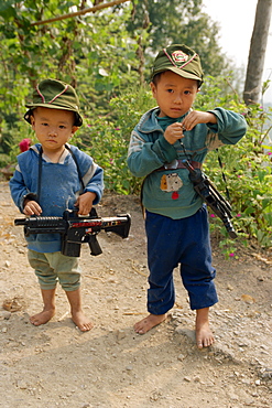 Portrait of two boys with modern toy guns in Guizhou, China, Asia