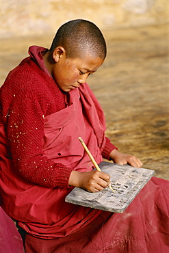 Young Buddhist monk practising writing, Bhutan, Asia