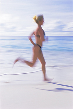 Blurred motion image of a woman jogging on the beach, Mahe Island, Seychelles, Indian Ocean, Africa