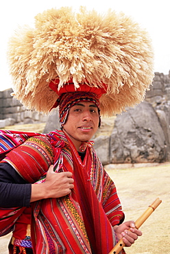 Portrait of a young Peruvian man in traditional dress, with hat and flute, Sacsayhuaman, near Cuzco, Peru, South America