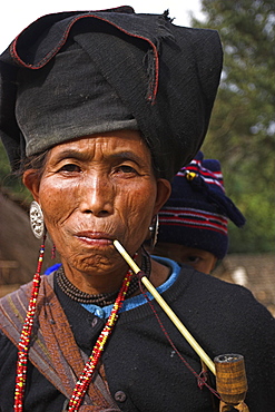 Wan Sai village (Aku tribe), Aku lady with baby on her back smoking wooden pipe, Kengtung (Kyaing Tong), Shan State, Myanmar (Burma), Asia