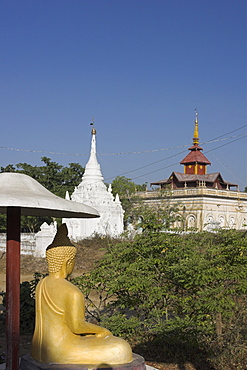 Buddha image sitting under parasol near pagodas, Salay, Myanmar (Burma), Asia