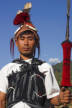 Naga man holding spear and wearing headdress of woven cane decorated with wild boar teeth, bear fur, red dyed goats hair and hornbill feathers, Naga New Year Festival, Lahe village, Sagaing Division, Myanmar (Burma), Asia