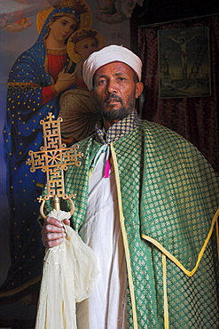 Priest with cross, Bet Meskel, an excavated chapel in the northern wall of the courtyard of Bet Maryam, Lalibela, Ethiopia, Africa