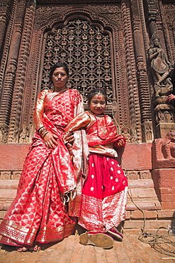 Mother and daughter stand in temple doorway at Kumari (living goddess) festival, Durbar Square, Kathmandu, Nepal, Asia